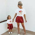 Woman and young girl wearing matching outfits with Santa Claus designs on a white background